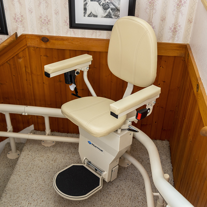 Lady riding Curved Stairlift with another lady assisting.